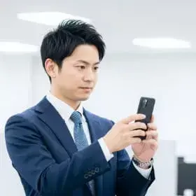 スーツ姿で真剣な表情でスマートフォンを操作する男性社員