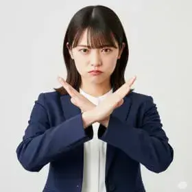 スーツ姿の女性が両腕を前で交差し、禁止や拒否を示すポーズをする